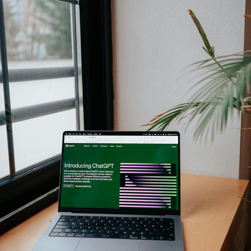 A laptop sitting on a wooden desk with a green screen