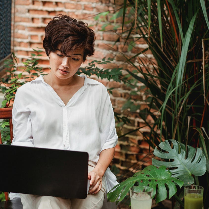 Pensive Asian woman using laptop in cafe