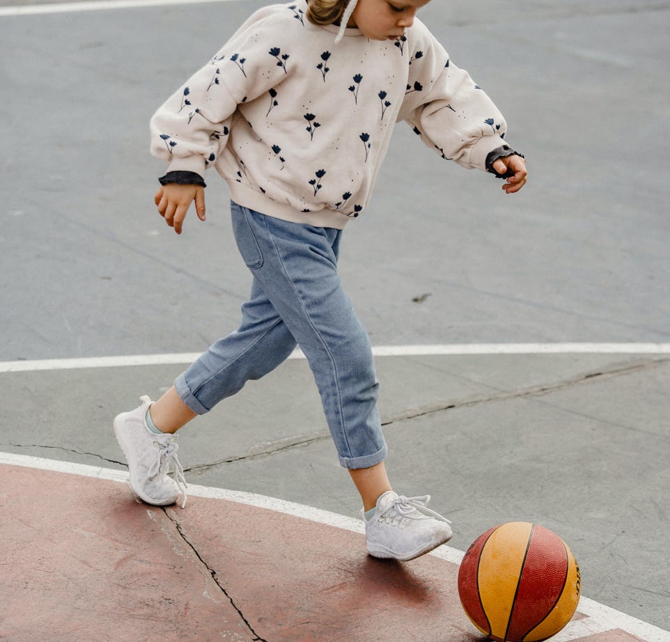 Cute girl walking after ball on sports ground