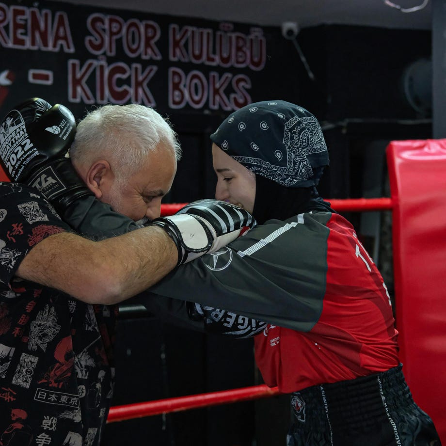 A man in a black shirt and gloves is boxing with a woman